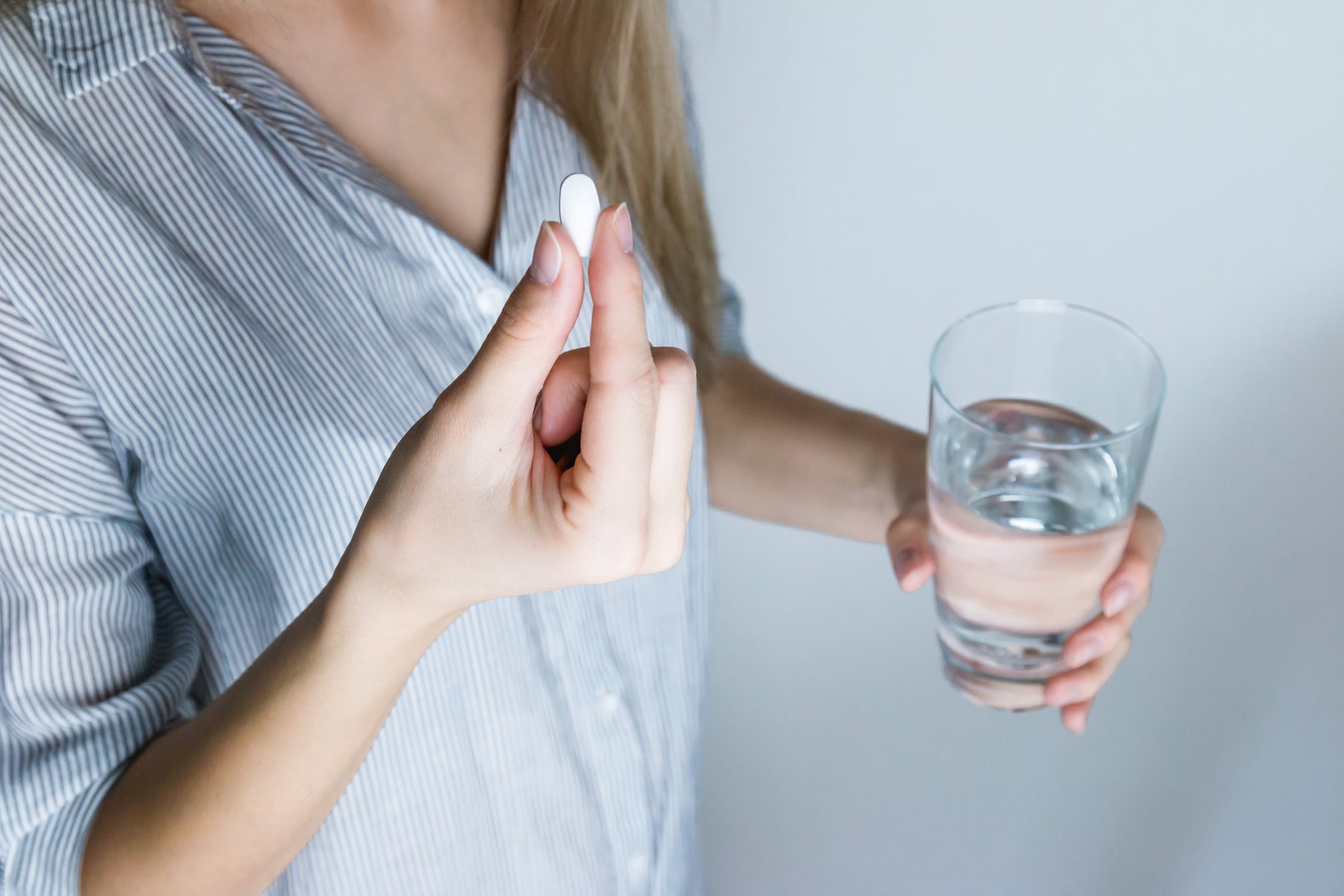 Kvinder tager en hovedpinepille med et glas vand